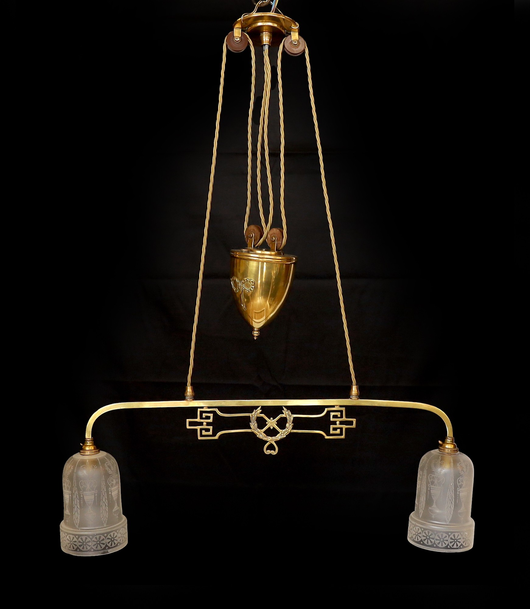 An Edwardian brass counter balanced light fitting with frosted glass shades etched with Grecian urns, height 80cm. width 64 cm